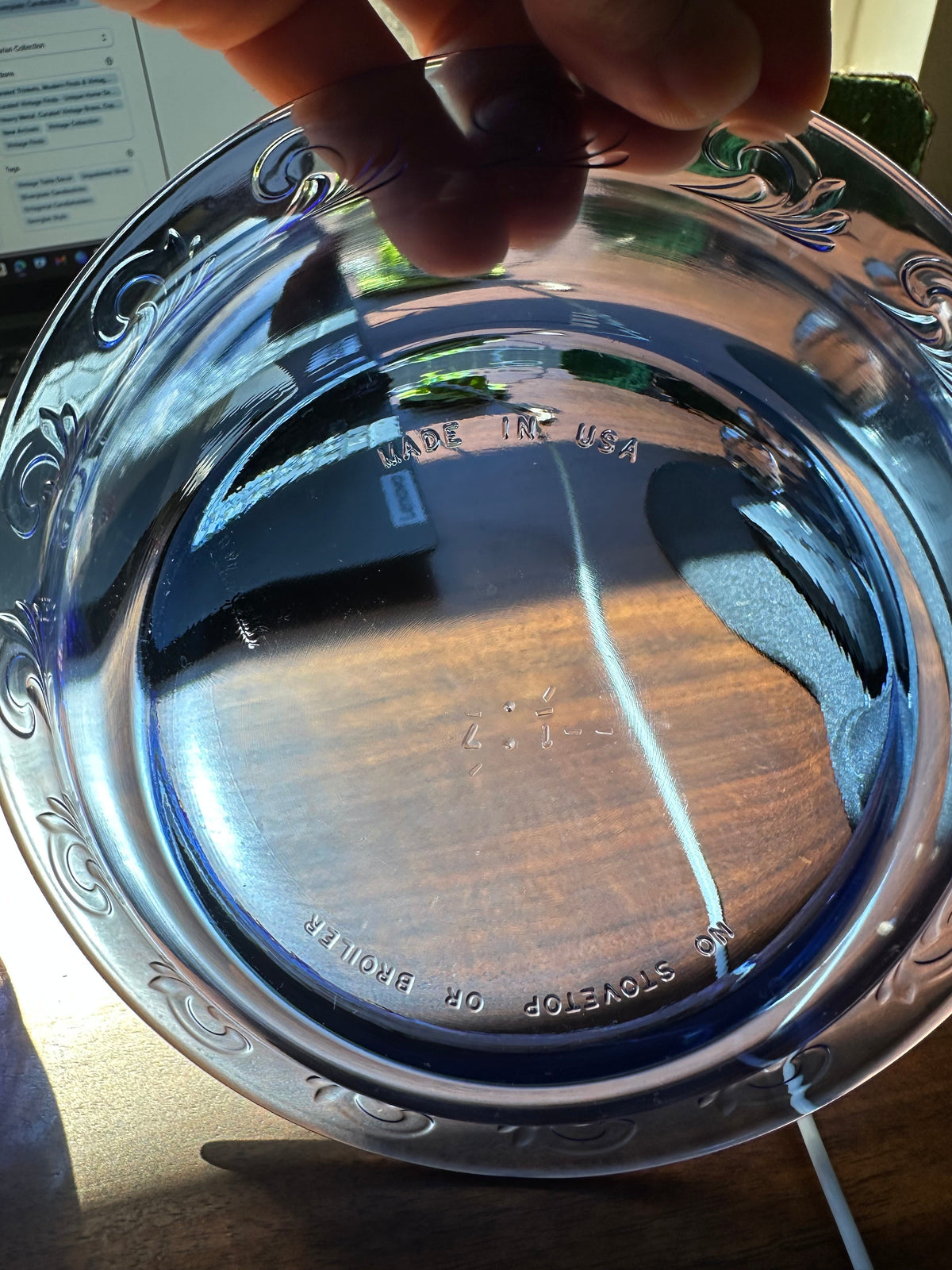 Cobalt blue glass dish held toward the light to show its underside, raised rim pattern, and molded manufacturing marks.