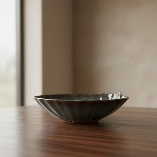 Three-quarter angle view of vintage fluted stoneware bowl with teal glaze on wood table in natural window light
