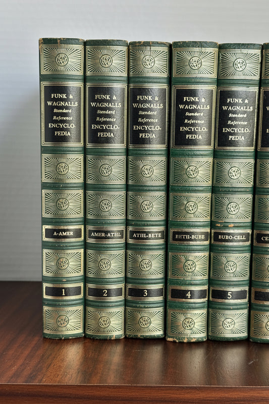 Close-up of vintage Funk and Wagnalls encyclopedia spines volumes 1 through 5 showing gilded black title labels A-AMER through BUBO-CELL, gold foil sunburst compartments, and globe motifs on deep green leatherette covers