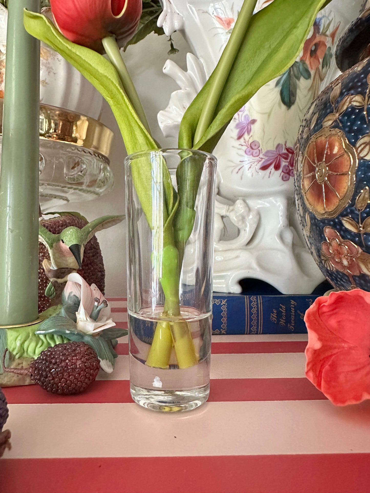 Clear glass vase with green stems on a decorative surface