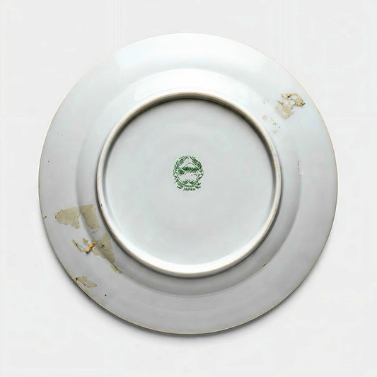 The underside of a vintage porcelain plate showing a green stamped backmark of Mount Fuji inside a wreath, reading Hand Painted Japan, with estate patina.