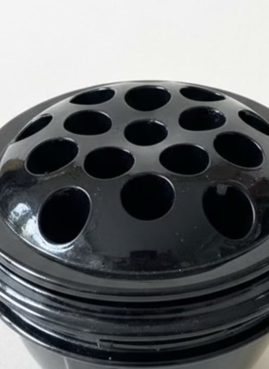 Black flower frog cylindrical container with multiple holes on a white background