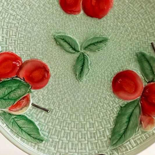 Ceramic plate with cherry design, green background, textured surface, vibrant colors, decorative homeware.