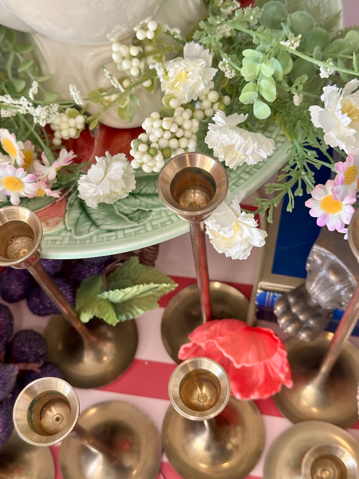 Decorative setup with brass candlesticks, flowers, and a colorful background