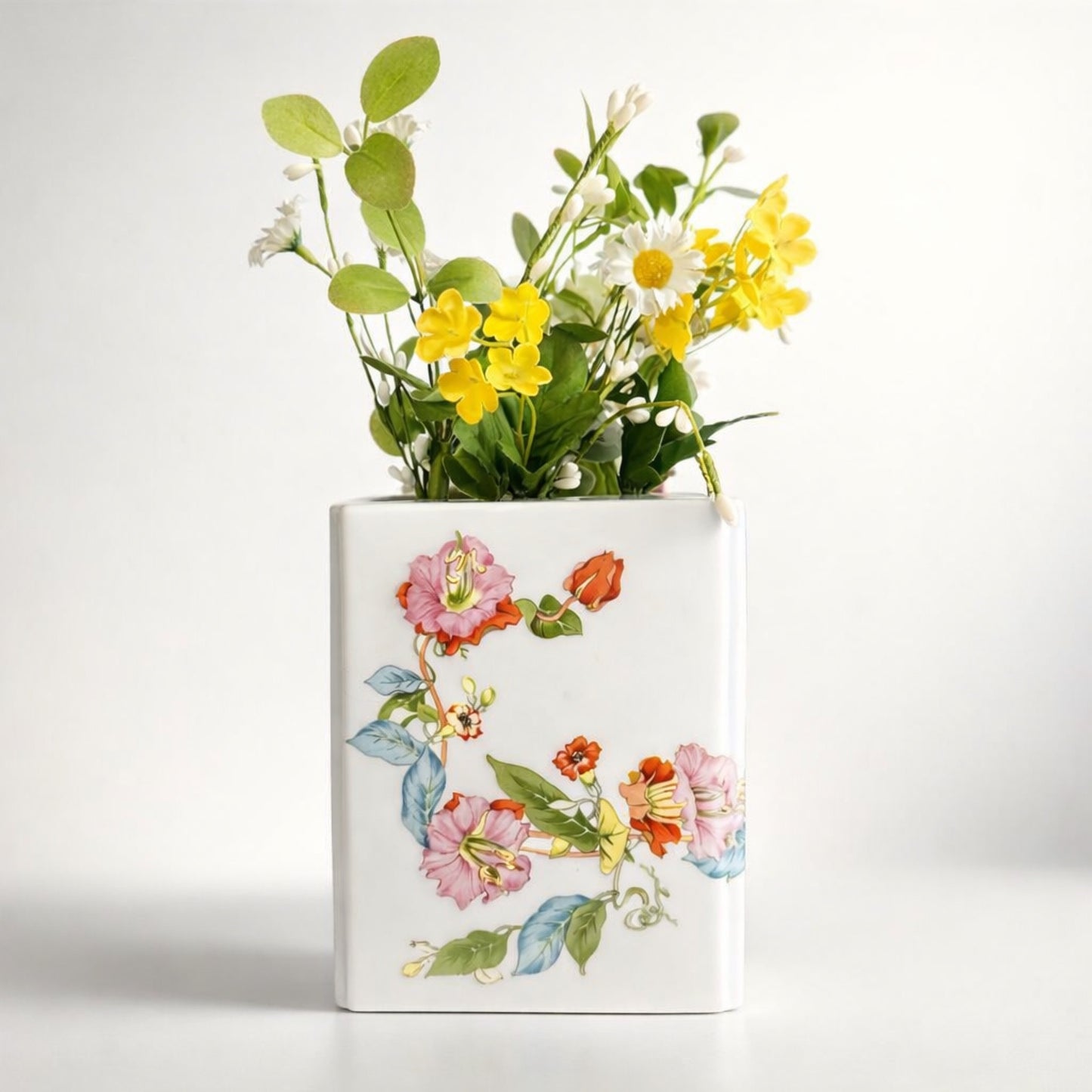 Decorative vase with floral design and artificial flowers on a white background