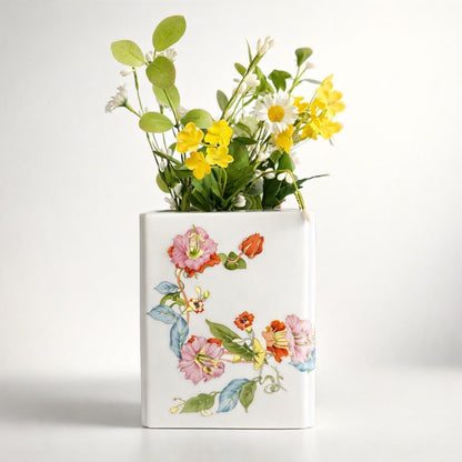 Decorative vase with floral design and artificial flowers on a white background