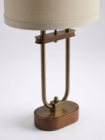 Close-up of a mid-century table lamp showcasing the antiqued brass u-frame, brass top plate, and rounded dark walnut wooden base.
