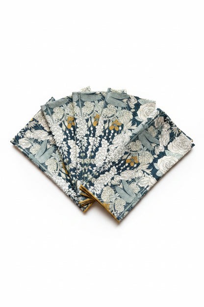 Set of four Dragonflies at Twilight cloth napkins fanned out, showing hand-printed floral and botanical design in navy, teal, and gold on 100% cotton
