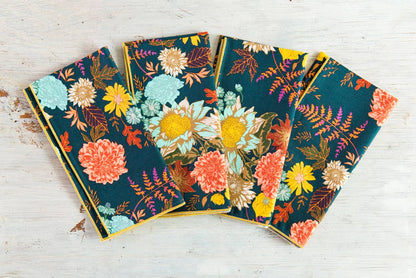 Set of four floral-patterned notebooks on a wooden surface