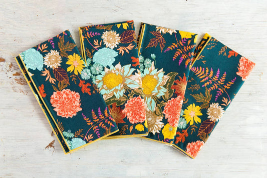 Set of four floral-patterned notebooks on a wooden surface