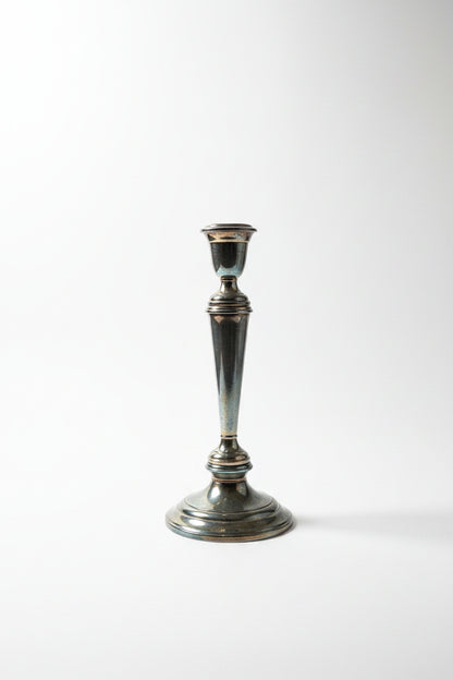 Gorham Newport silverplate convertible candelabra in single candlestick configuration showing tapered column, stepped circular base, and warm oxidized patina — arms removed, white background
