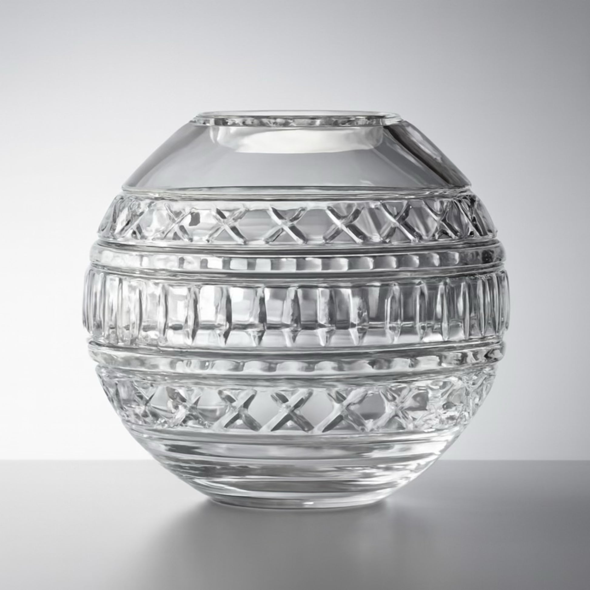 Spherical cut glass vase with etched bands and crisscross patterns, styled in soft natural light