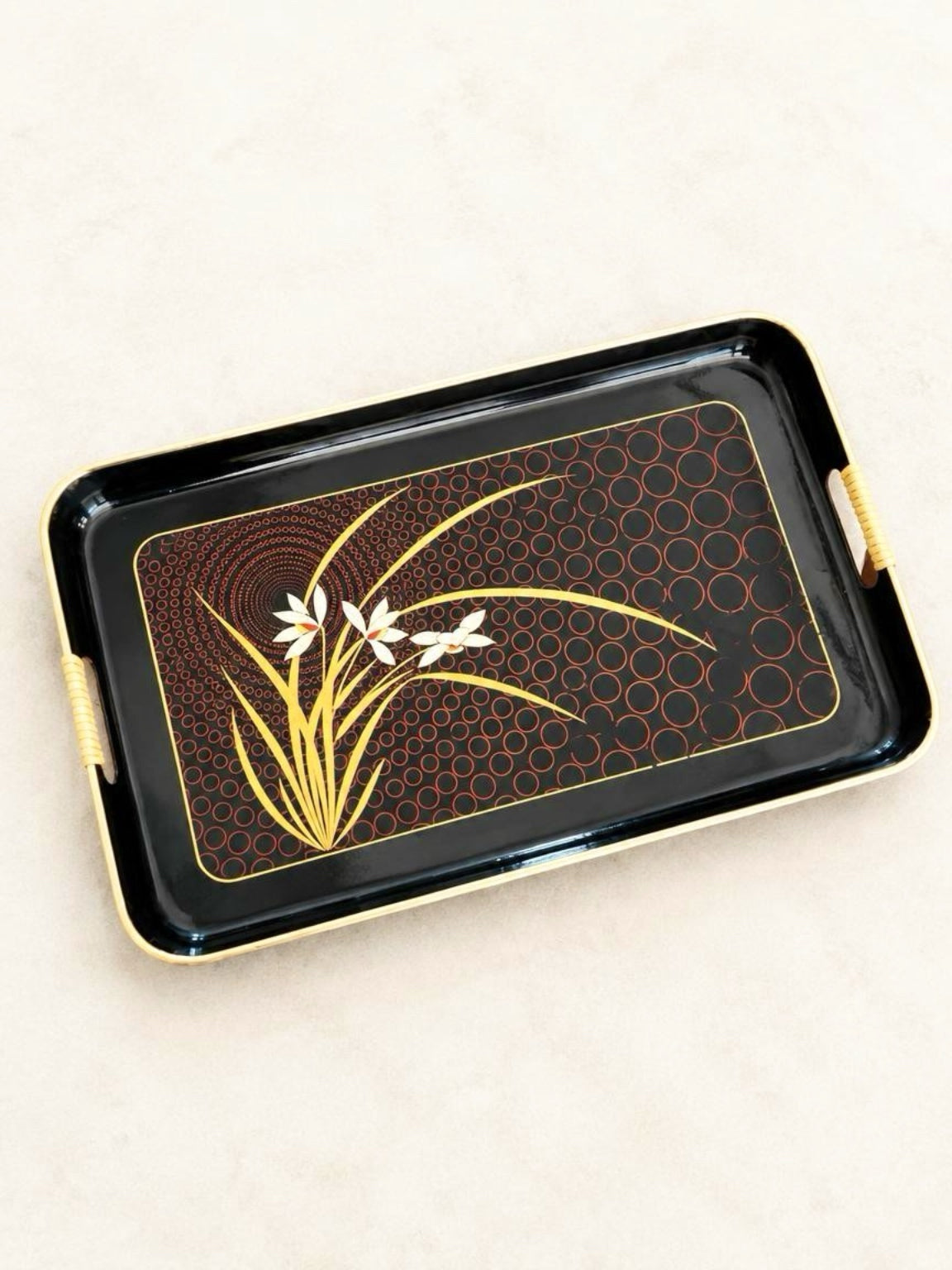 Vintage Japanese black lacquer serving tray with cream flowers, gold-tone leaves, red circular pattern, and cane handles.
