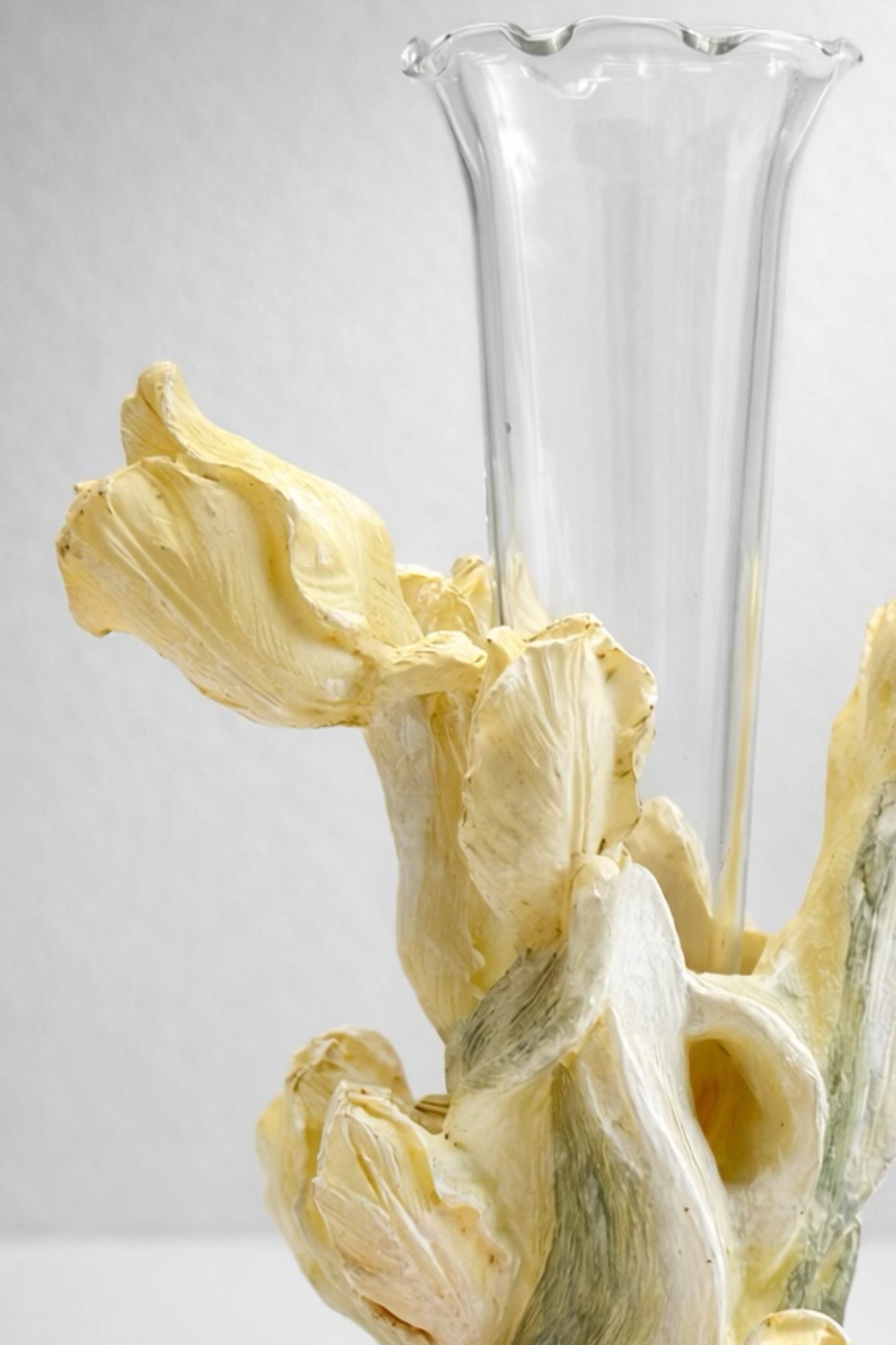 A 1960s vintage Japanese sculptural ceramic bud vase featuring dimensional, hand-painted pale yellow iris petals and green stems that wrap around a clear, removable fluted glass insert, styled against a neutral studio background.