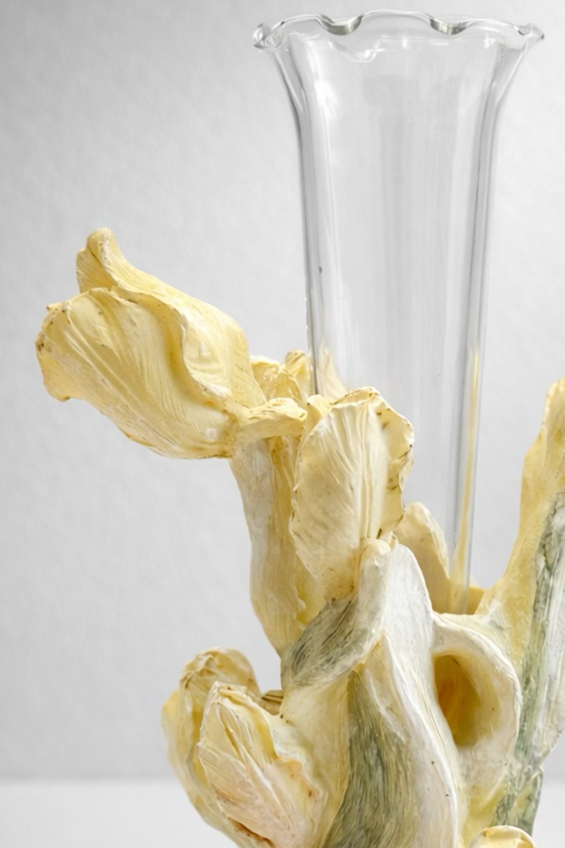 A 1960s vintage Japanese sculptural ceramic bud vase featuring dimensional, hand-painted pale yellow iris petals and green stems that wrap around a clear, removable fluted glass insert, styled against a neutral studio background.