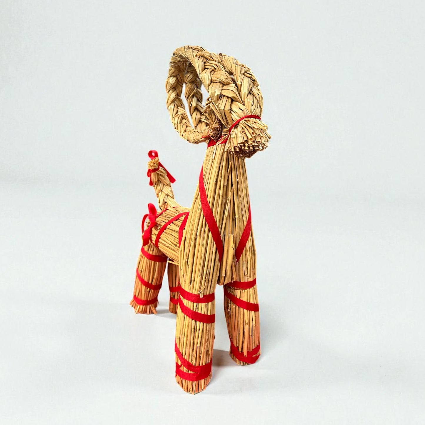 Woven straw dog toy with red accents on a white background