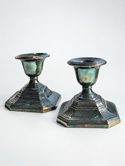 Pair of Georgian-style silverplate candlesticks with stepped octagonal bases, short stems, and dark iridescent tarnish.