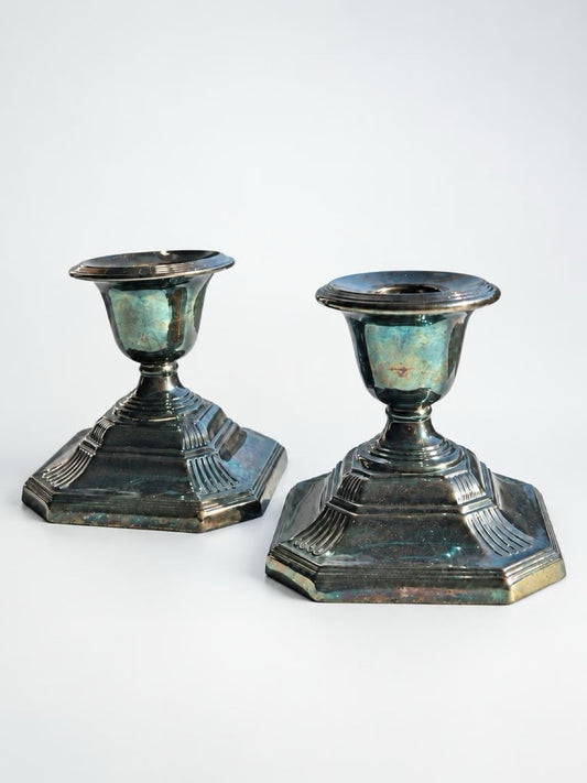 Pair of Georgian-style silverplate candlesticks with stepped octagonal bases, short stems, and dark iridescent tarnish.