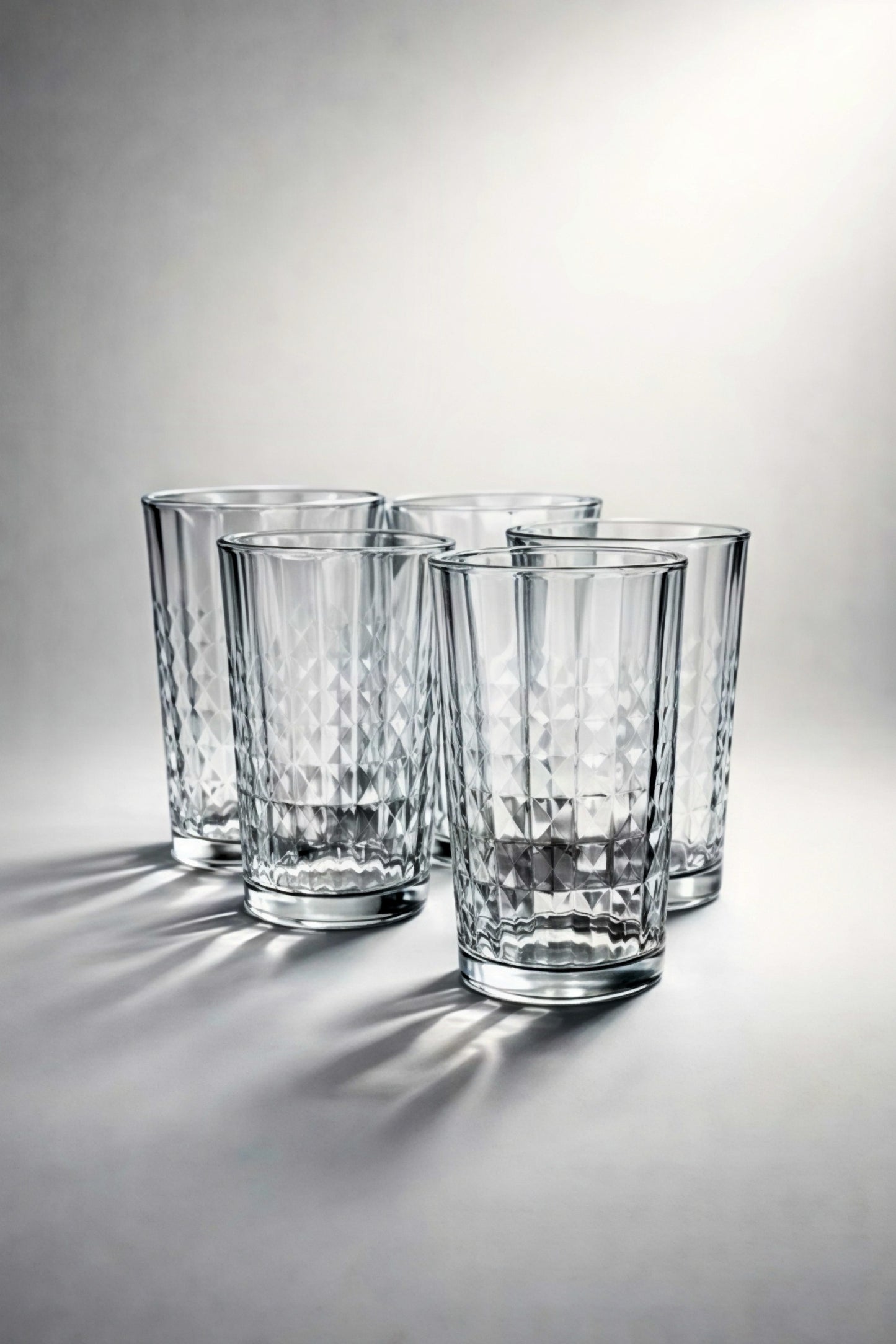Set of four clear glass tumblers on a light gray background
