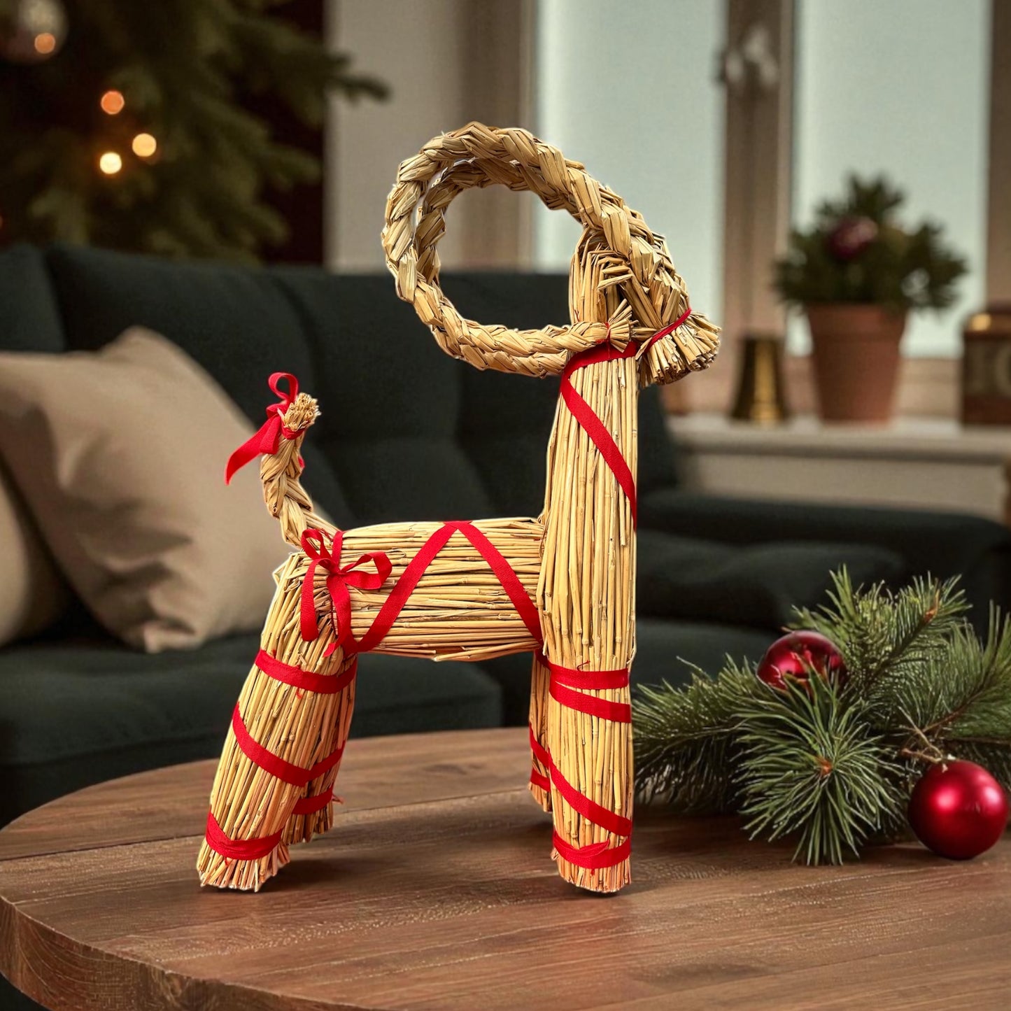 Decorative straw goat figure with red ribbons on a wooden table in a festive room.