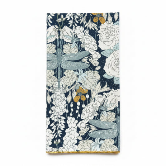 Single Dragonflies at Twilight napkin folded to show dragonfly motif detail, wisteria, and rose print on navy cotton with gold hem edge