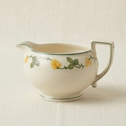 Ceramic creamer with floral design on a light background