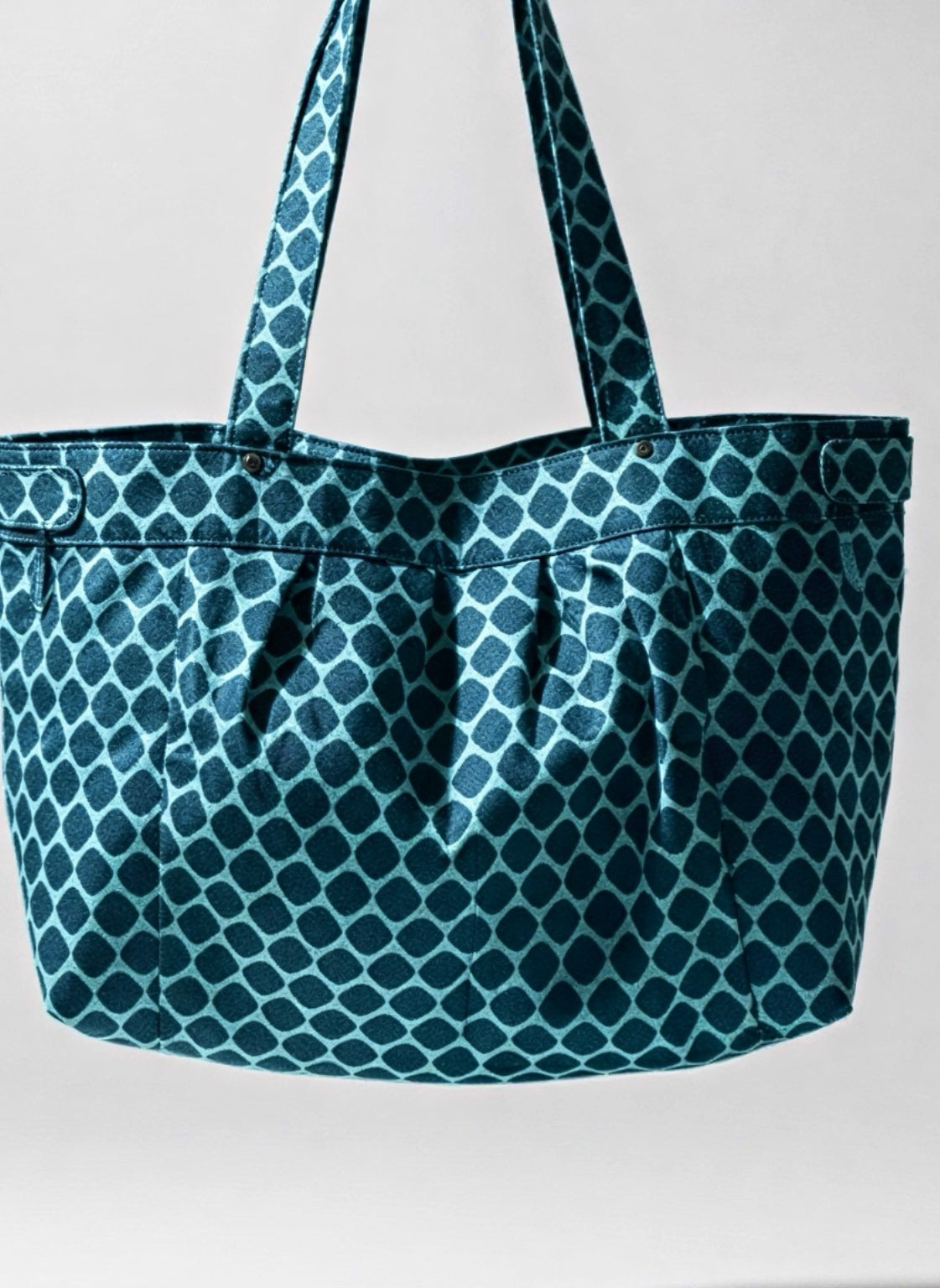 A teal and dark blue patterned tote bag with two shoulder straps, shown against a light gray background.