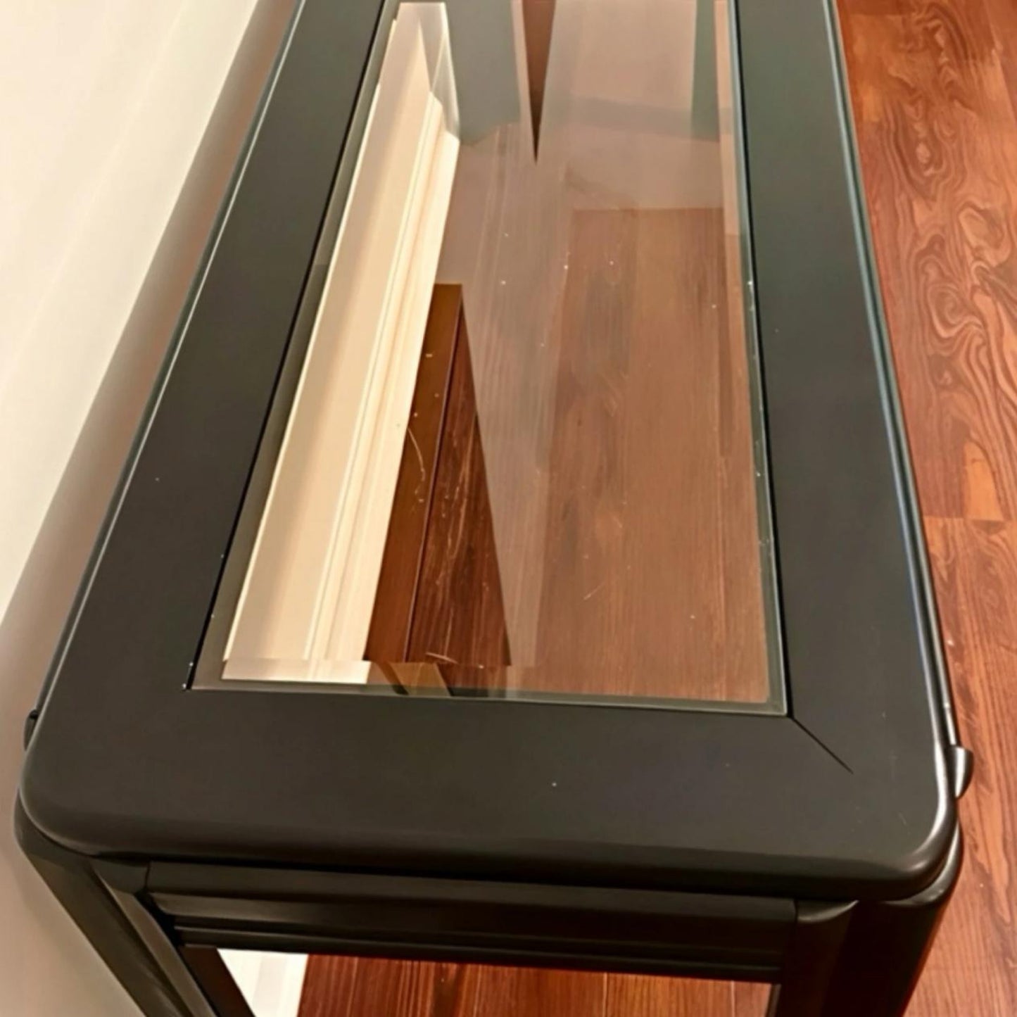 Black metal console table with a glass top, perfect for modern living spaces.