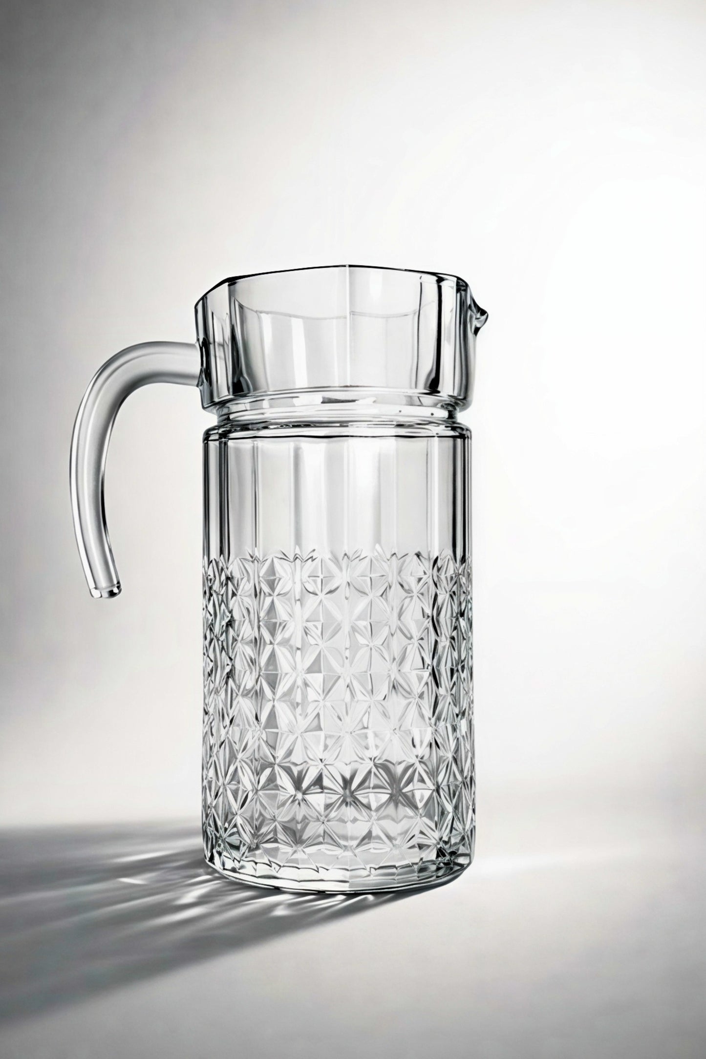 Clear glass pitcher with diamond pattern on a light gray background