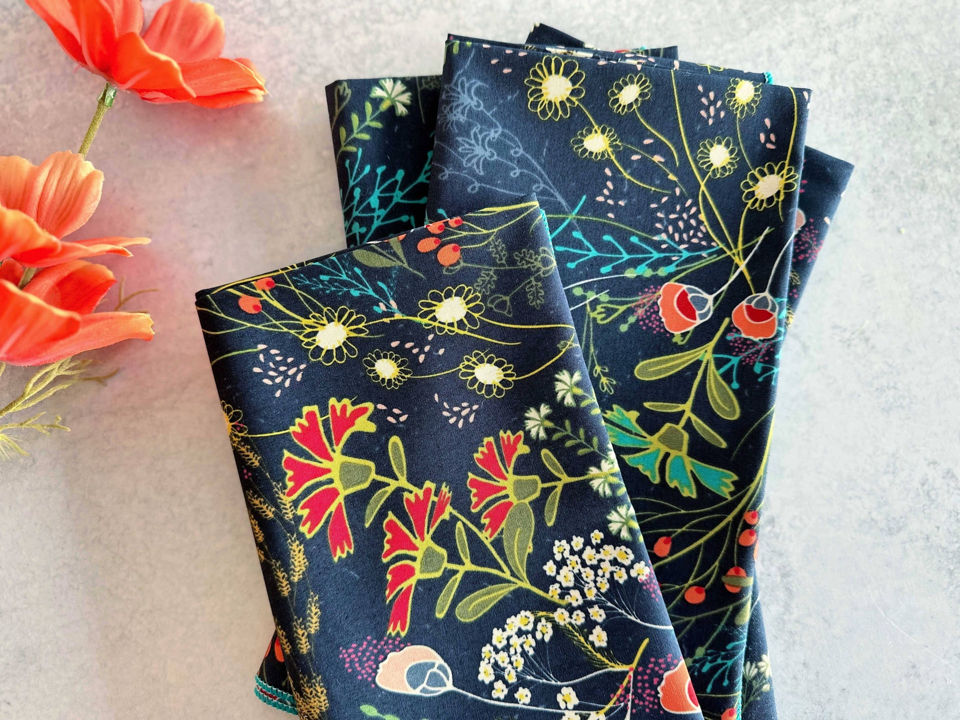 Floral patterned cotton napkins in navy blue, featuring colorful botanical designs.