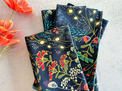 Floral patterned cotton napkins in navy blue, featuring colorful botanical designs.