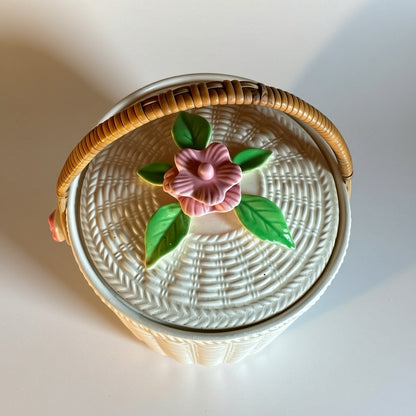 Vintage white basket with pink flower lid and woven handle, ideal for decorative storage.
