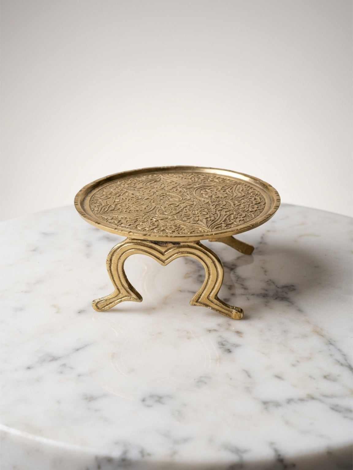 Decorative gold stand with intricate design on a marble surface
