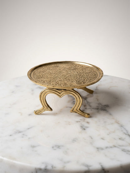 Decorative gold stand with intricate design on a marble surface
