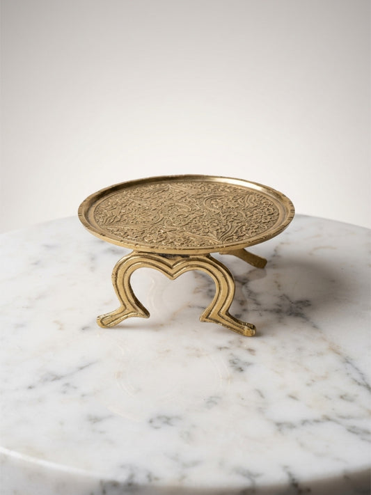 Decorative gold stand with intricate design on a marble surface