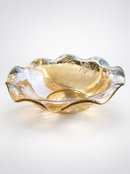 Vintage Jeannette Floragold amber glass bowl with a ruffled rim and shimmering iridescent finish.
