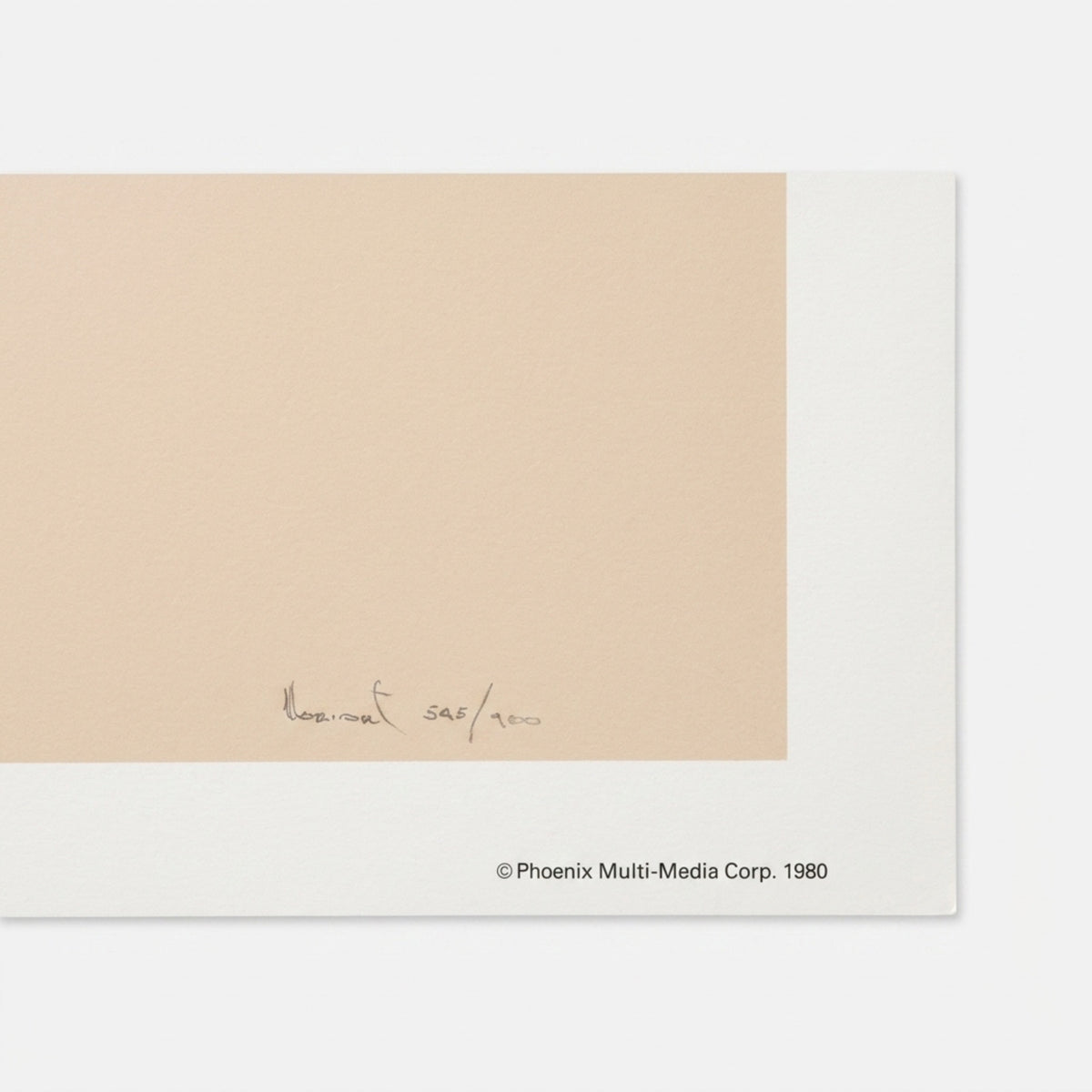 A close-up detail shot of the lower right white border margin of a vintage 1980 lithograph print. It features a hand-written pencil signature and limited edition numbering 545/900. The crisp white paper edge is stamped with a black text copyright notice reading "Phoenix Multi-Media Corp. 1980". The unframed art print rests flat on a natural golden oak wood grain table background.