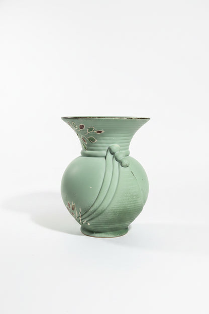 Alternate view of a vintage art pottery vase in matte sage green on a crisp white backdrop. This side highlights detailed hand-painted tube-lined illustrations of stylized crocus or tulip flowers in soft orange, yellow, and white at the base, with slender brown branches extending up to the flared rim.