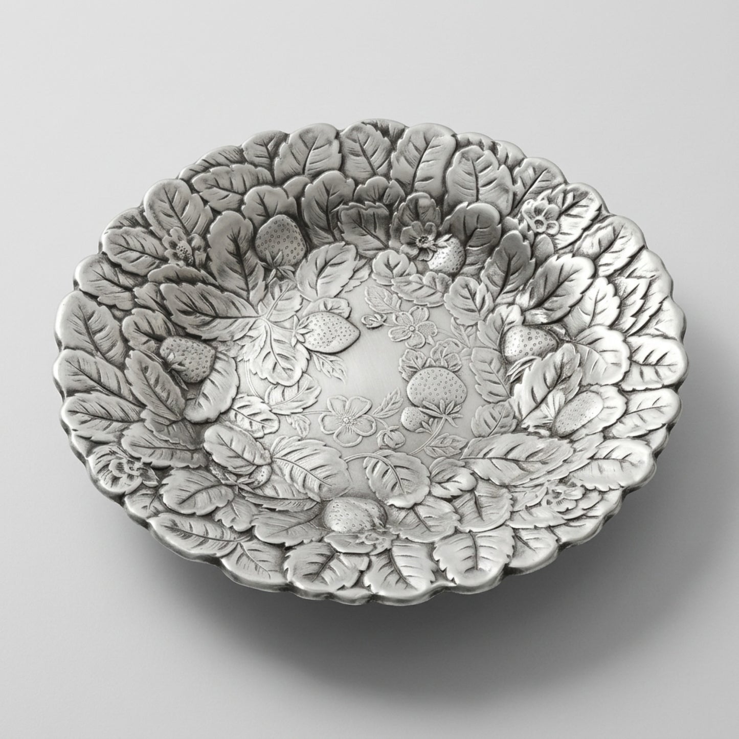 An angled profile edit of a mid century silverplate tray with an embossed berry motif serving bowl design.
