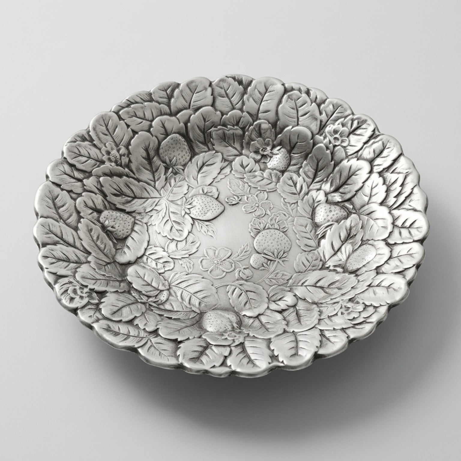 An angled profile edit of a mid century silverplate tray with an embossed berry motif serving bowl design.