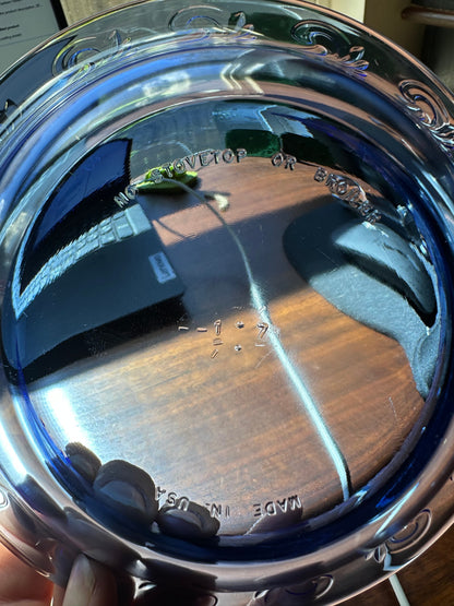 Close-up of a cobalt blue glass dish underside showing molded “Made in USA” and “No stovetop or broiler” markings.
