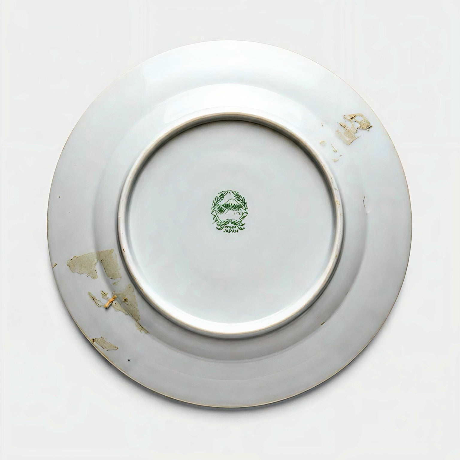 The underside of a vintage porcelain plate showing a green stamped backmark of Mount Fuji inside a wreath, reading Hand Painted Japan, with estate patina.