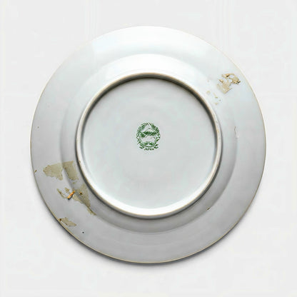 The underside of a vintage porcelain plate showing a green stamped backmark of Mount Fuji inside a wreath, reading Hand Painted Japan, with estate patina.