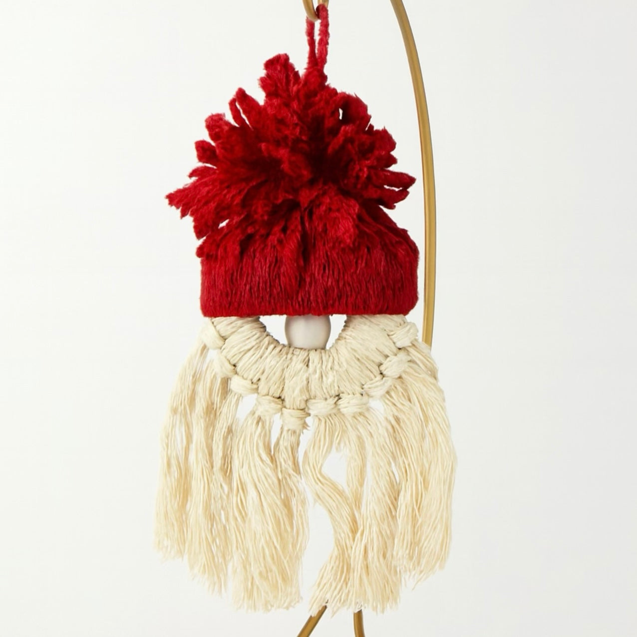 Decorative hanging figure with a red knitted hat and beige tassels on a white background