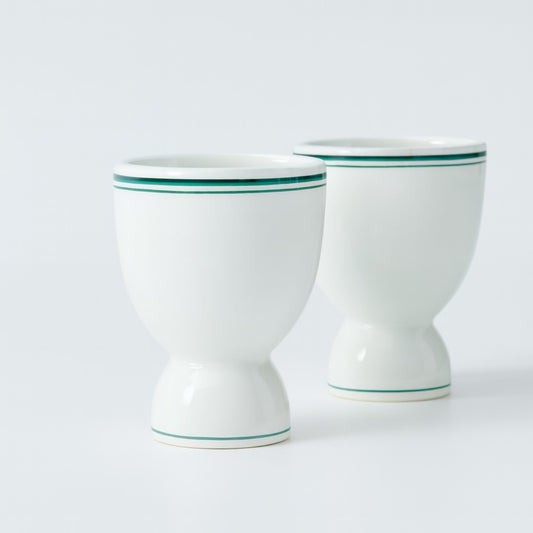 Set of two elegant white porcelain egg cups with green stripes, perfect for breakfast dining.