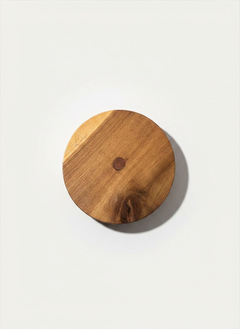 Underside view of a handcrafted vintage wood box showing the natural grain and a faint handwritten artist signature on the edge.