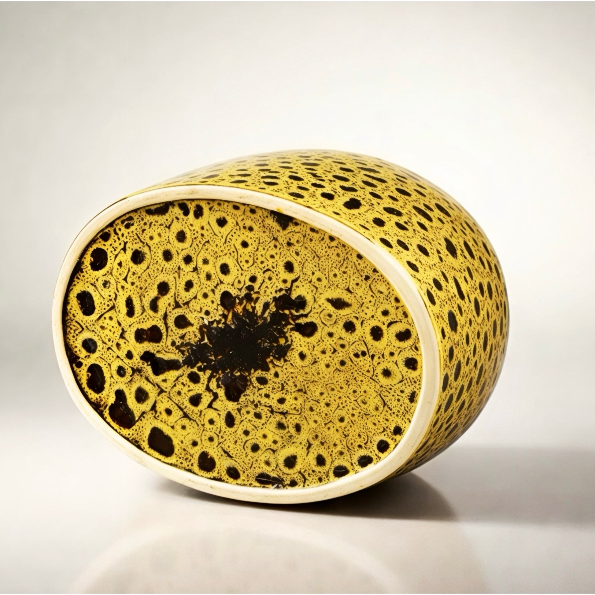 Decorative cylindrical object with a textured surface on a light gray background