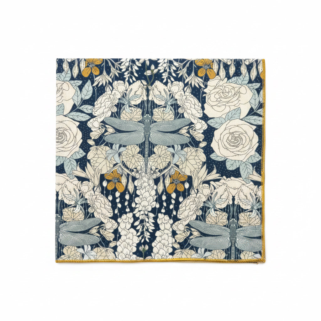 Dragonflies at Twilight cloth napkin laid flat showing full mirrored dragonfly and rose print in navy, cream, teal, and mustard gold with finished edges