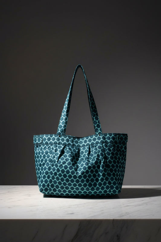 A teal and white patterned tote bag with two shoulder straps, shown floating against a light gray background with a soft shadow underneath.