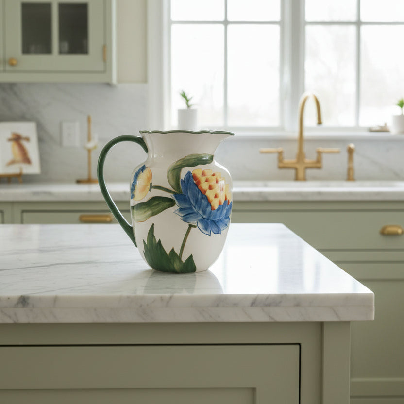 Ceramic pitcher with floral design on a marble counter top in a light green kitchen
